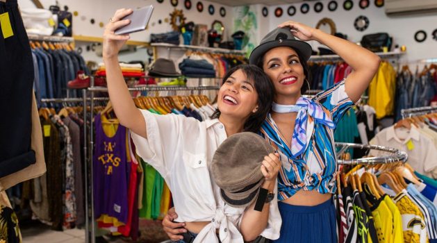 cheerful-friends-trying-on-hat-in-shop-and-taking-2023-11-27-04-56-22-utc (1) (1)